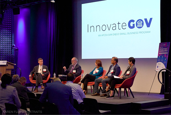 People seated on a stage for a panel at the InnovateGov conference